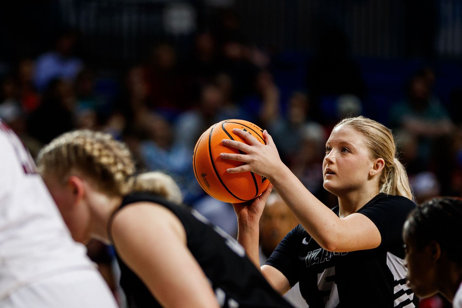Team members reach for the basketball during a fast-paced indoor game.