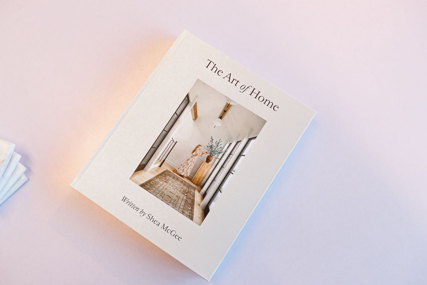 Lifestyle book titled 'The Art of Home' on light pink background.