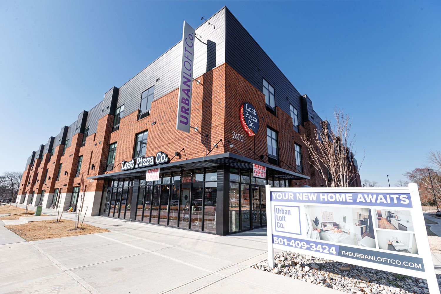 Modern red brick commercial building with retail space on ground floor and apartments above.