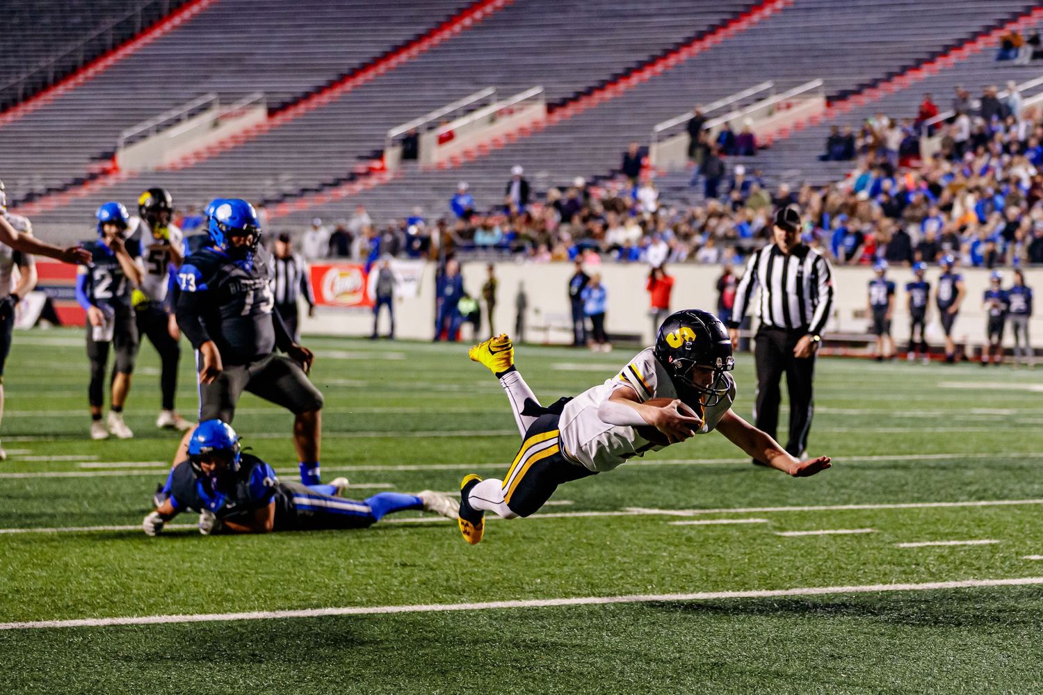 Athletic play sequence shows football players diving and tackling on the turf field.