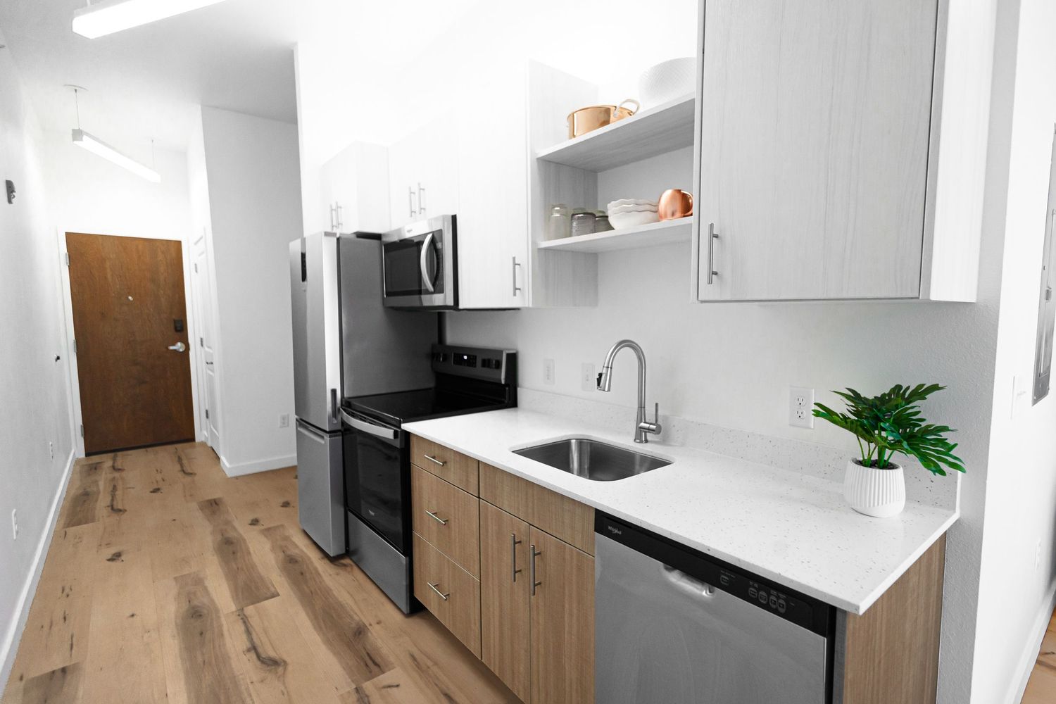 Sleek kitchen with wood cabinets, white countertops, and stainless appliances in open layout.