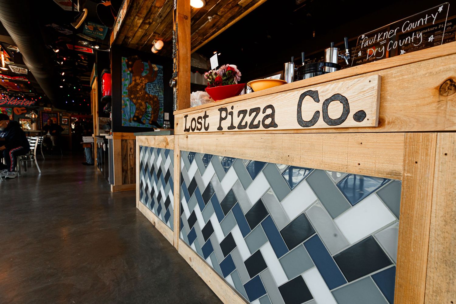 Modern bar counter with geometric pattern and Lost Pizza Co. branding.