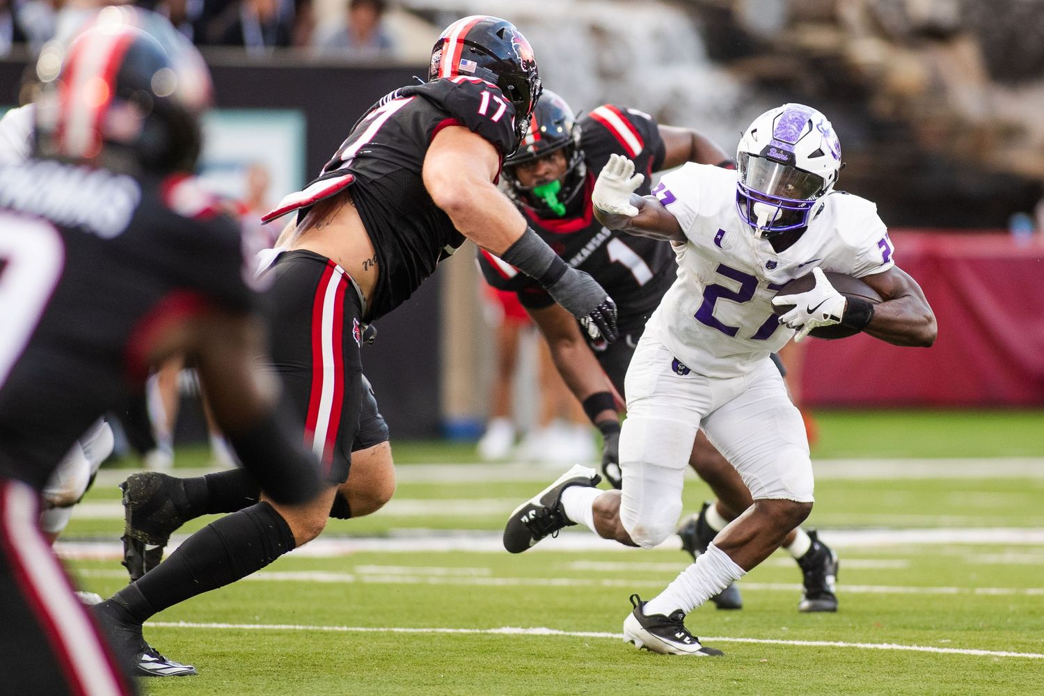 Football players colliding in tackle during competitive game play.