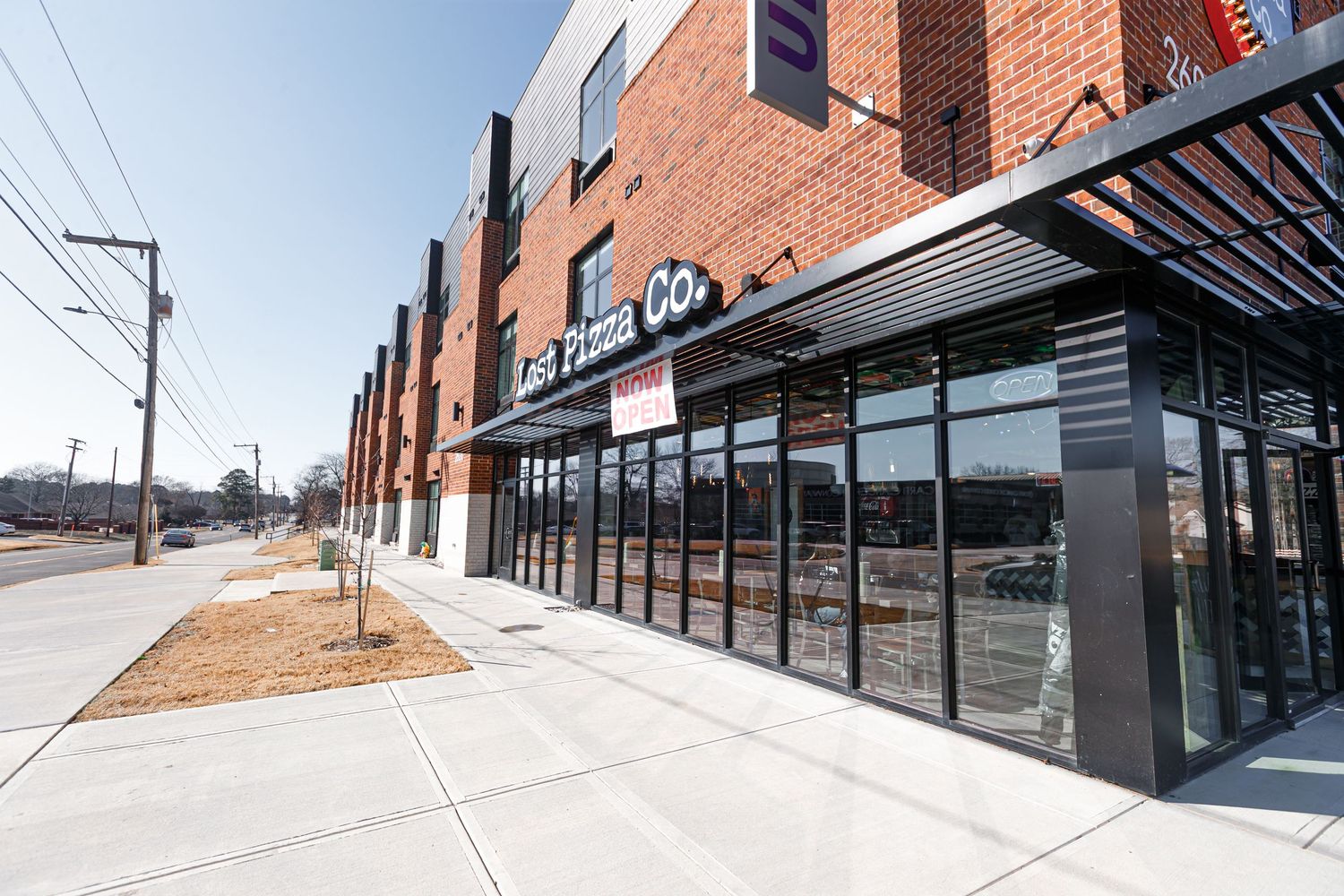 Wide angle view of Lost Pizza Co. storefront with large windows and modern architecture.