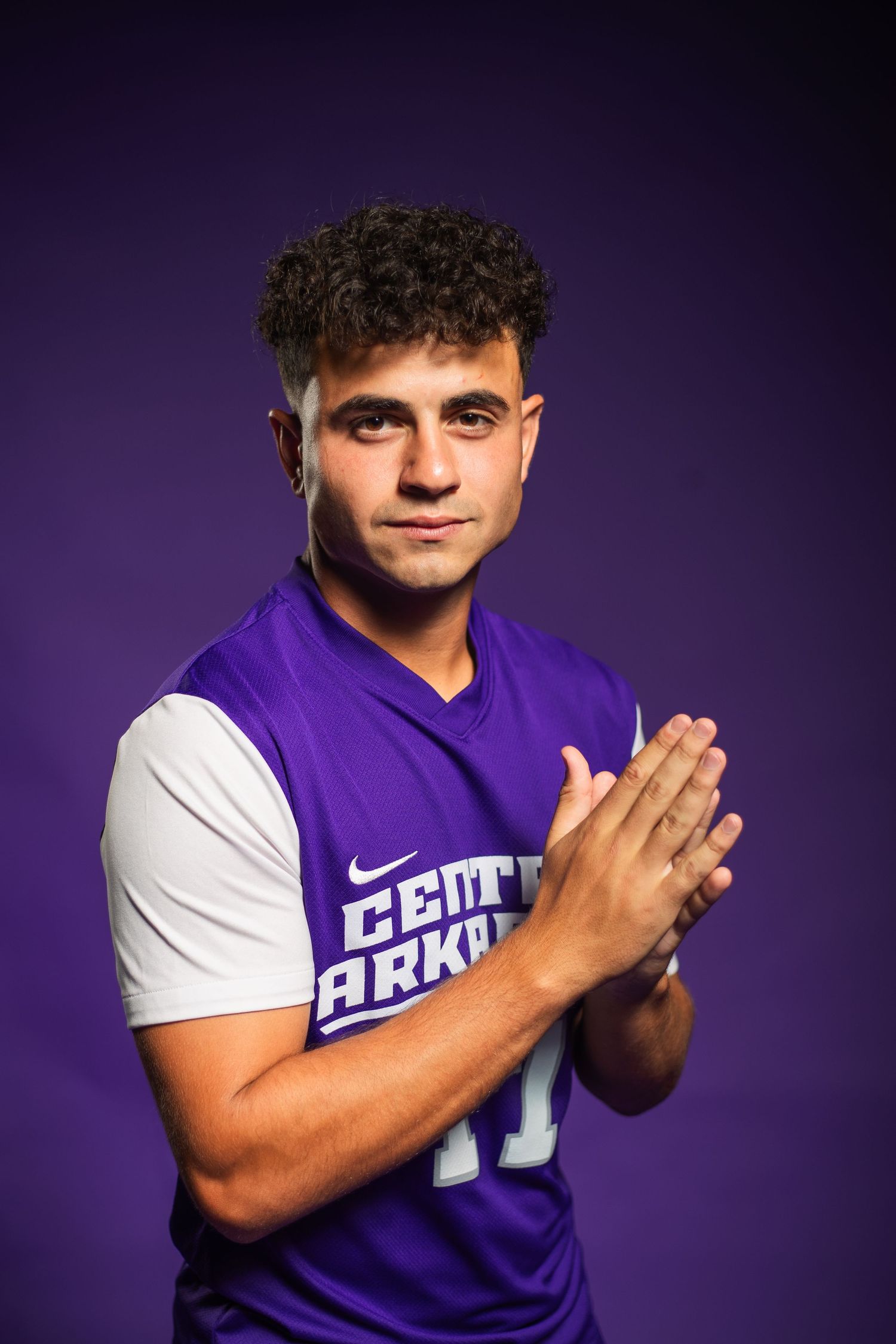 Athlete in purple and white sports uniform striking dynamic poses against dark background.