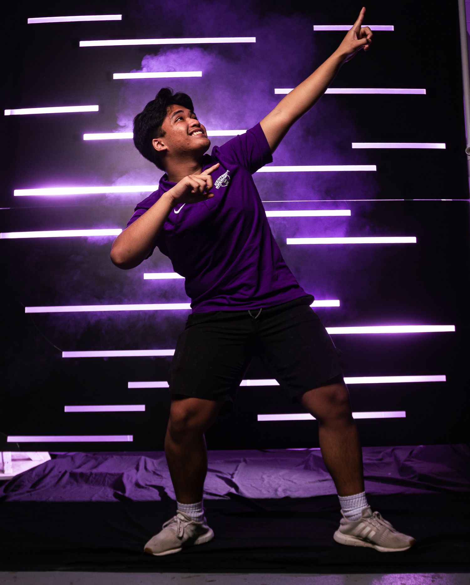 Athletic poses against purple neon backdrop with dramatic lighting effects.