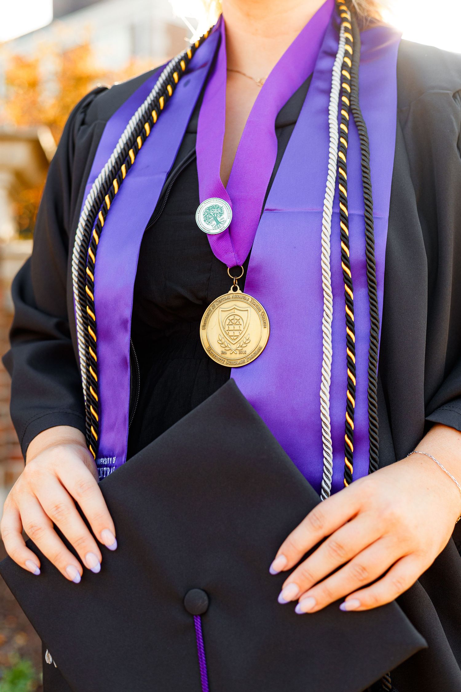 Close up of graduation stole with gold honor cords and medallion.