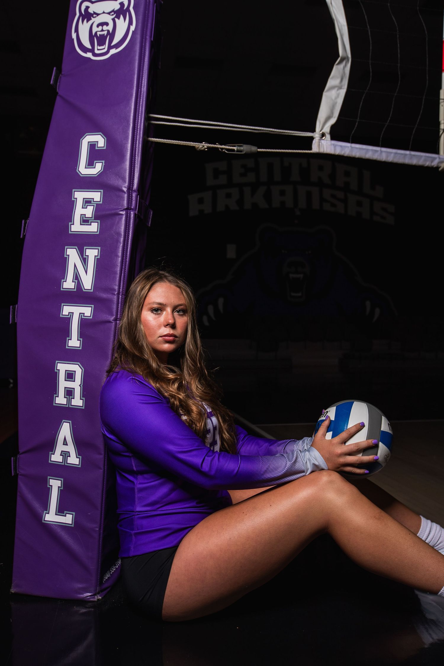 Athletic photo series with volleyball player posing with ball against purple gym backdrop.