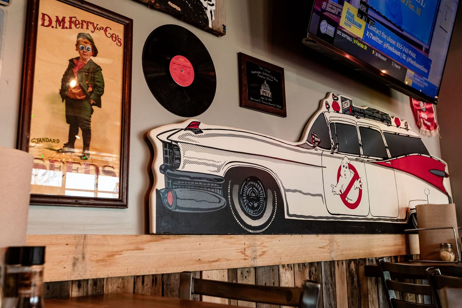 Vintage style wall decor featuring Ghostbusters car artwork and vinyl records in a restaurant.