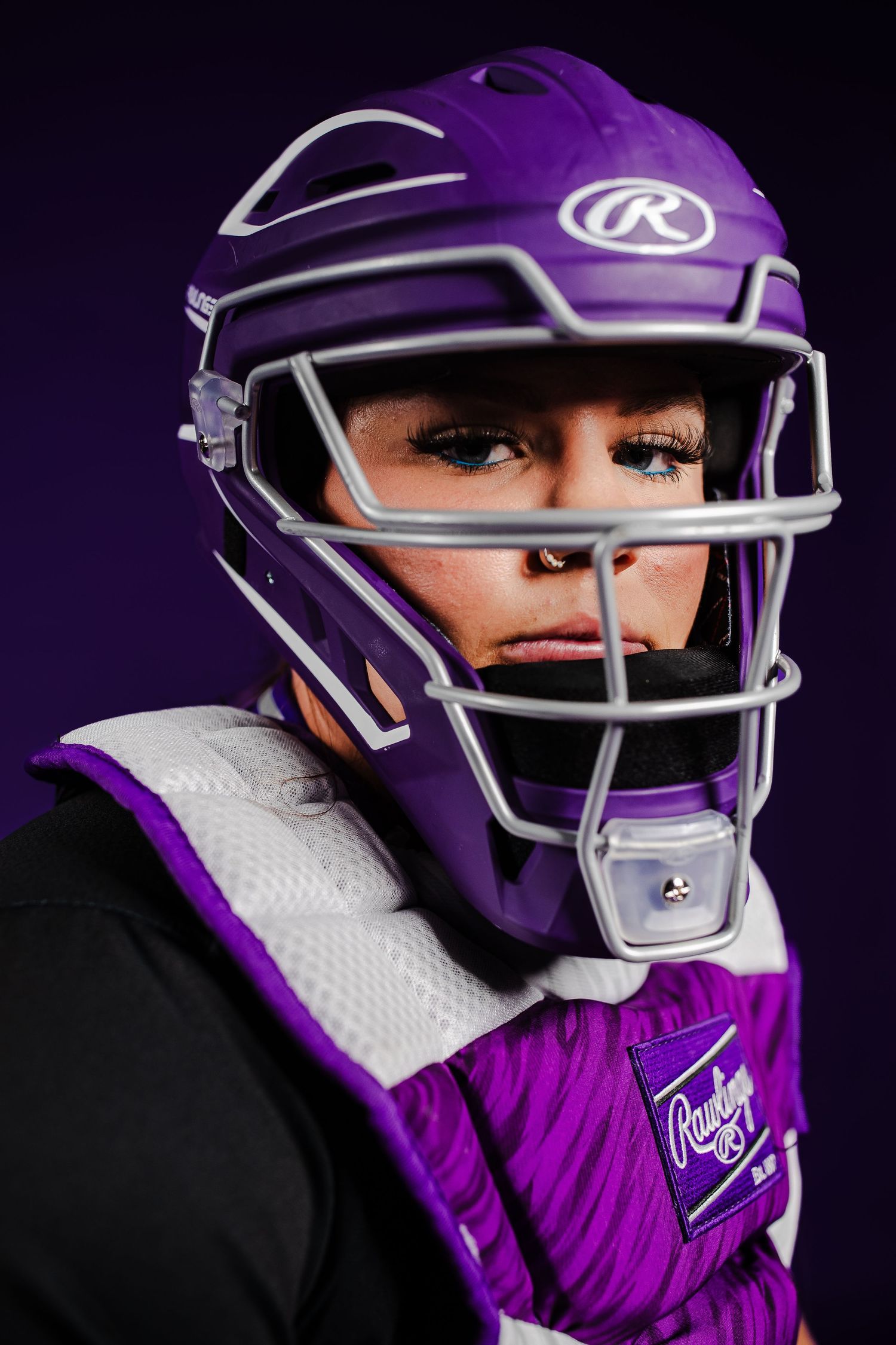 Close up shots of purple sports helmet with protective face mask against dark background.