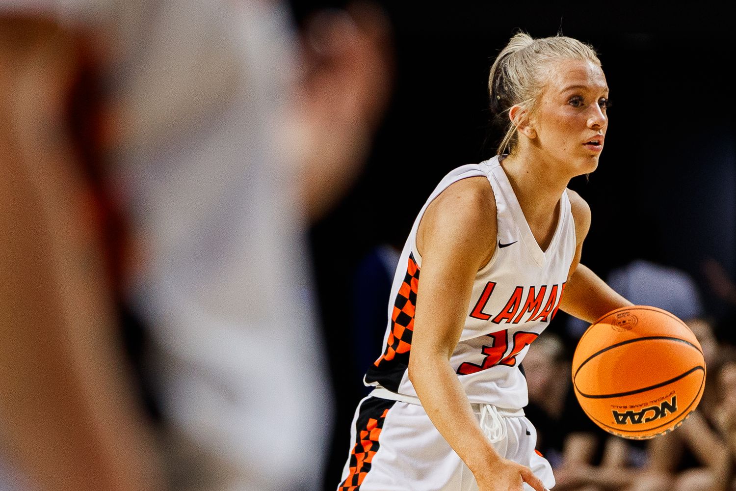 Female basketball player dribbling ball during competitive game.