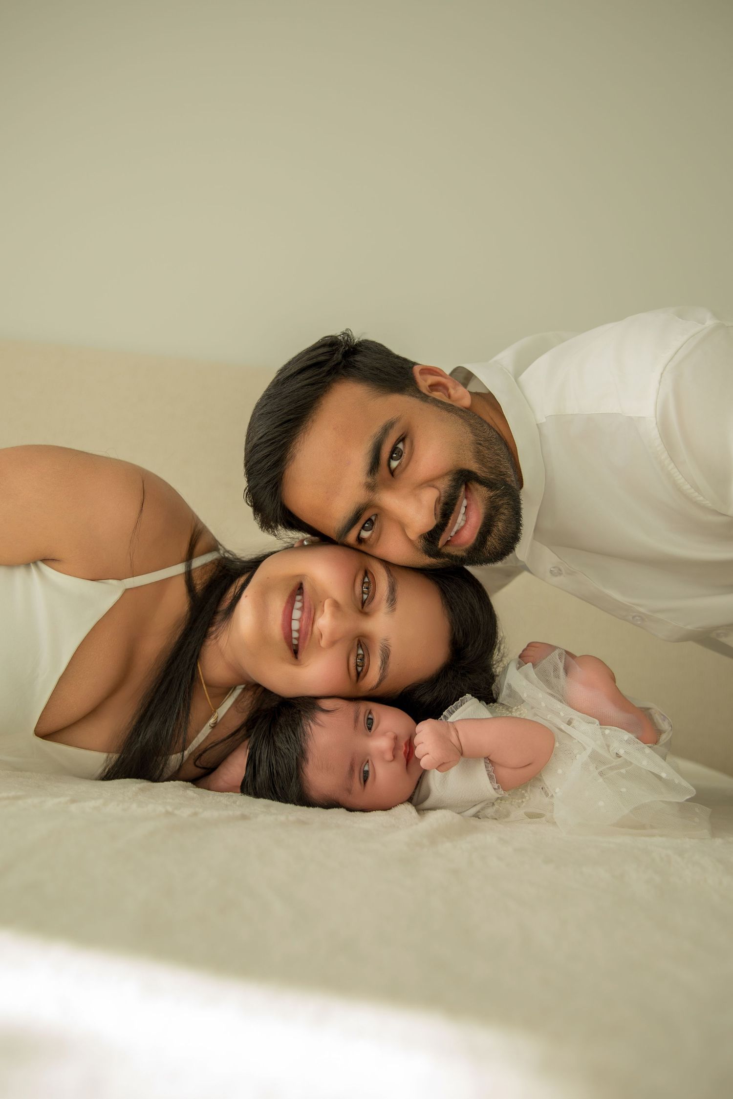 A tender family moment captured against a neutral backdrop in a photography studio setting.