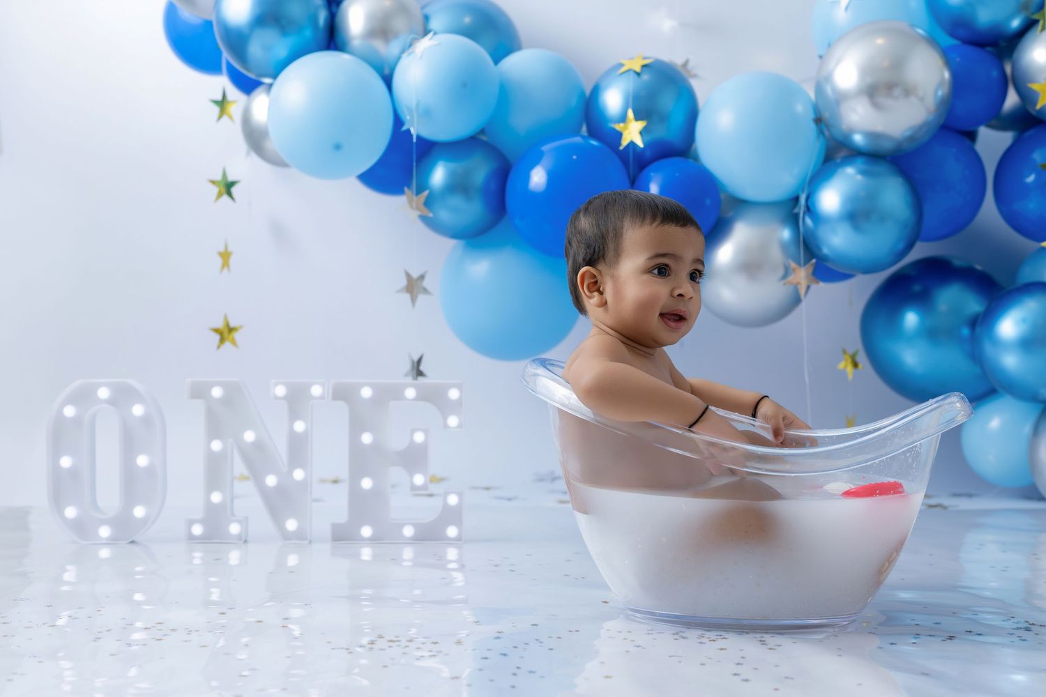 Blue and silver balloon arch with gold star decorations against white background.