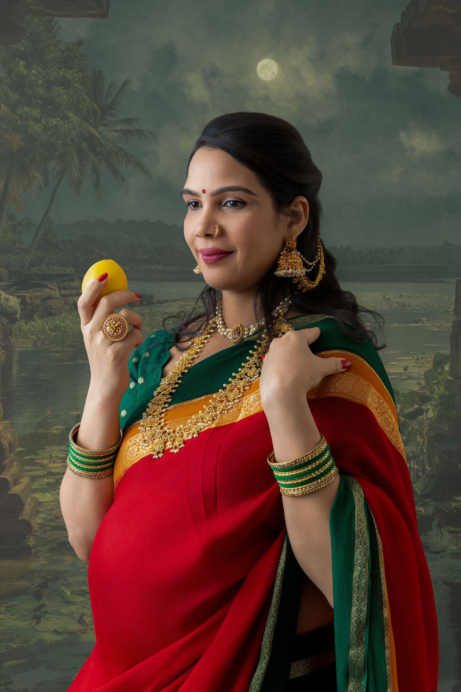 Indian woman in red saree with gold jewelry holding a mango, posing against moonlit tropical backdrop.