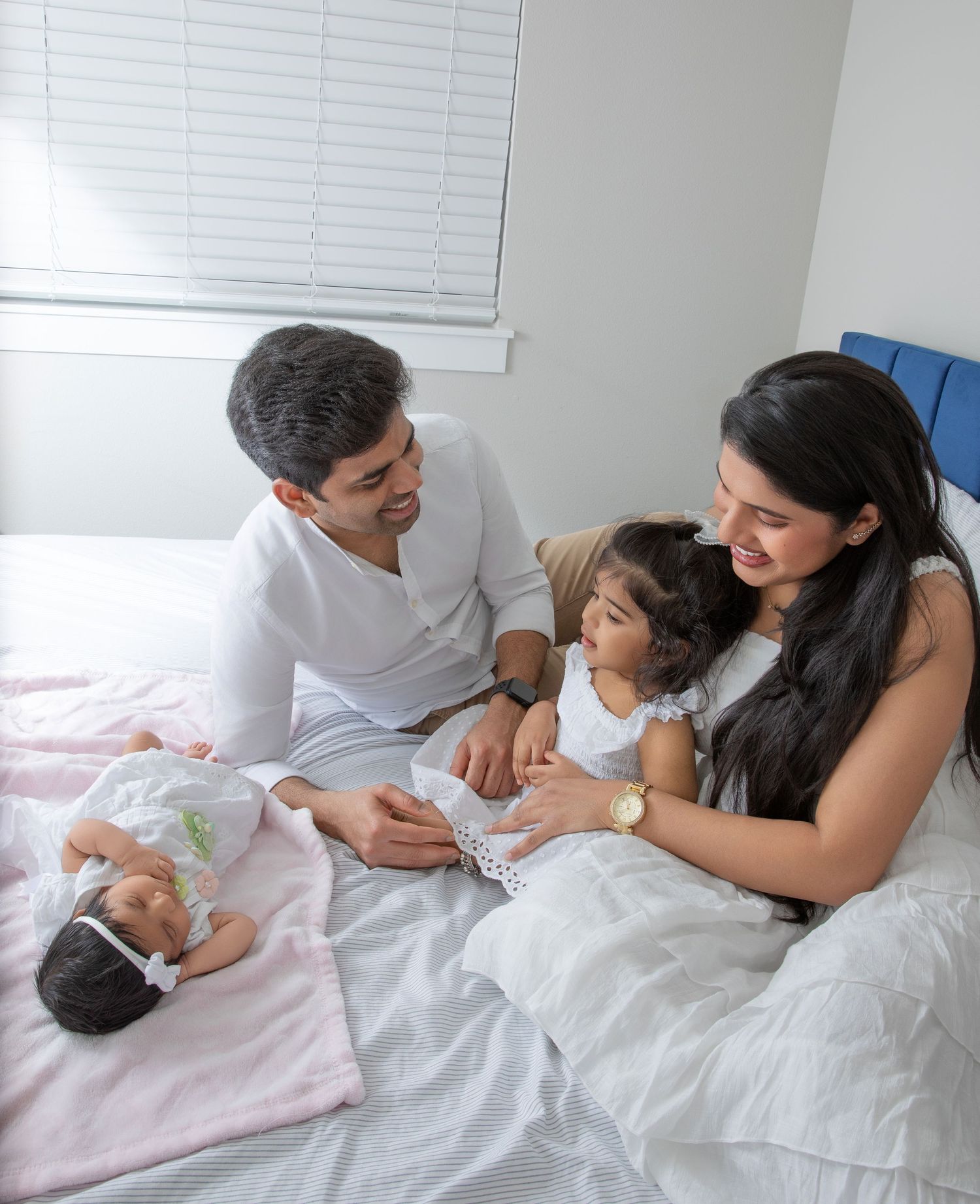 A series of intimate family moments showing parents bonding with a baby on a white bed.