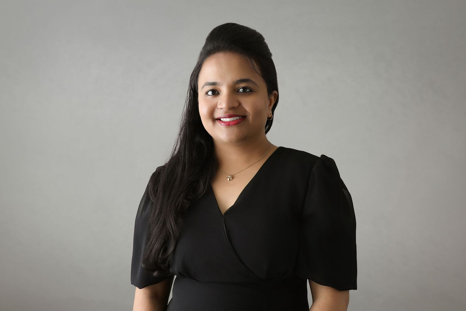 Studio portraits of woman in black dress against neutral gray background.