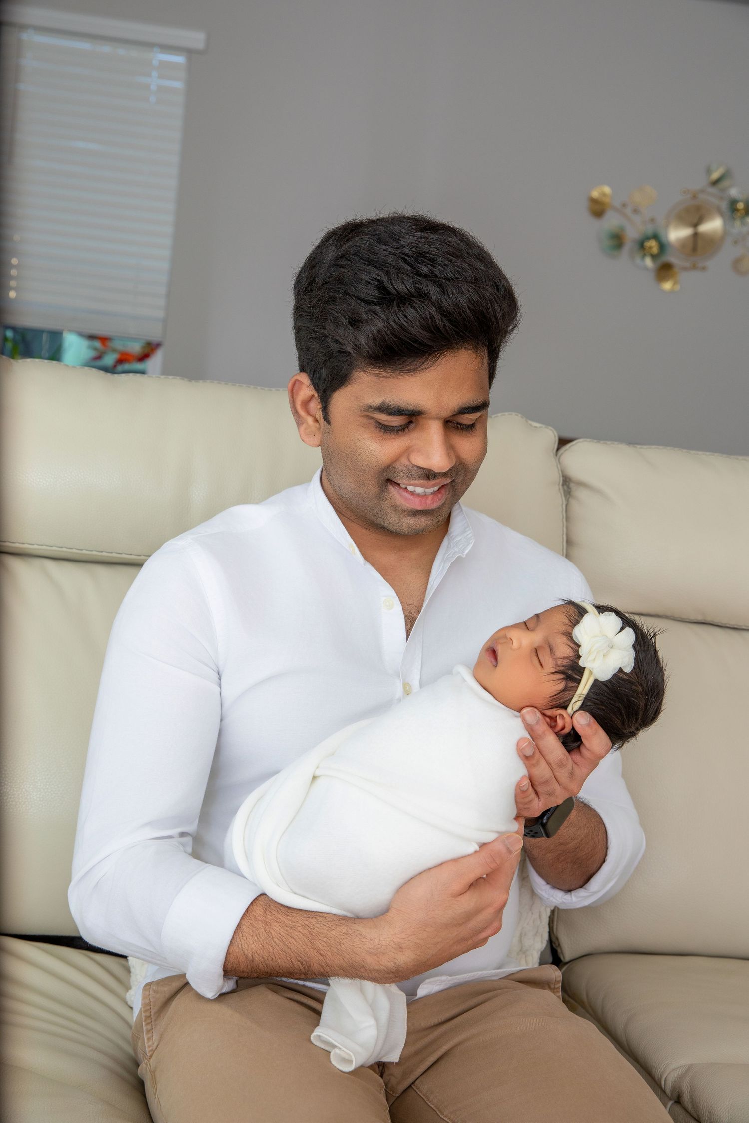 A series of five photos showing a person in a white shirt holding and bonding with a newborn baby on a light colored couch.