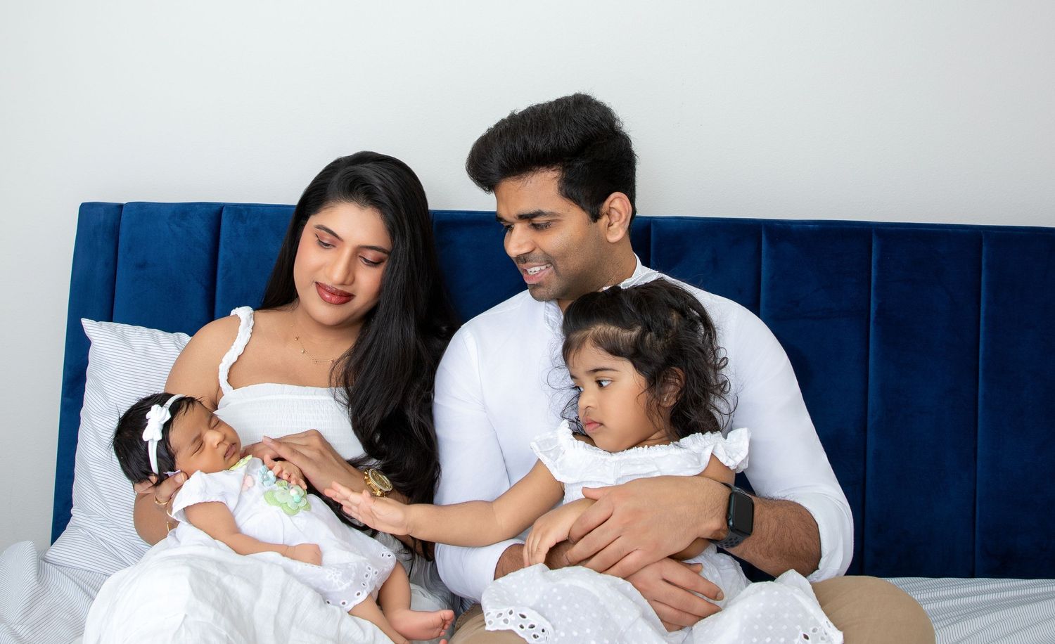 A collage of four images showing a family resting together on white bedding with navy blue decor.