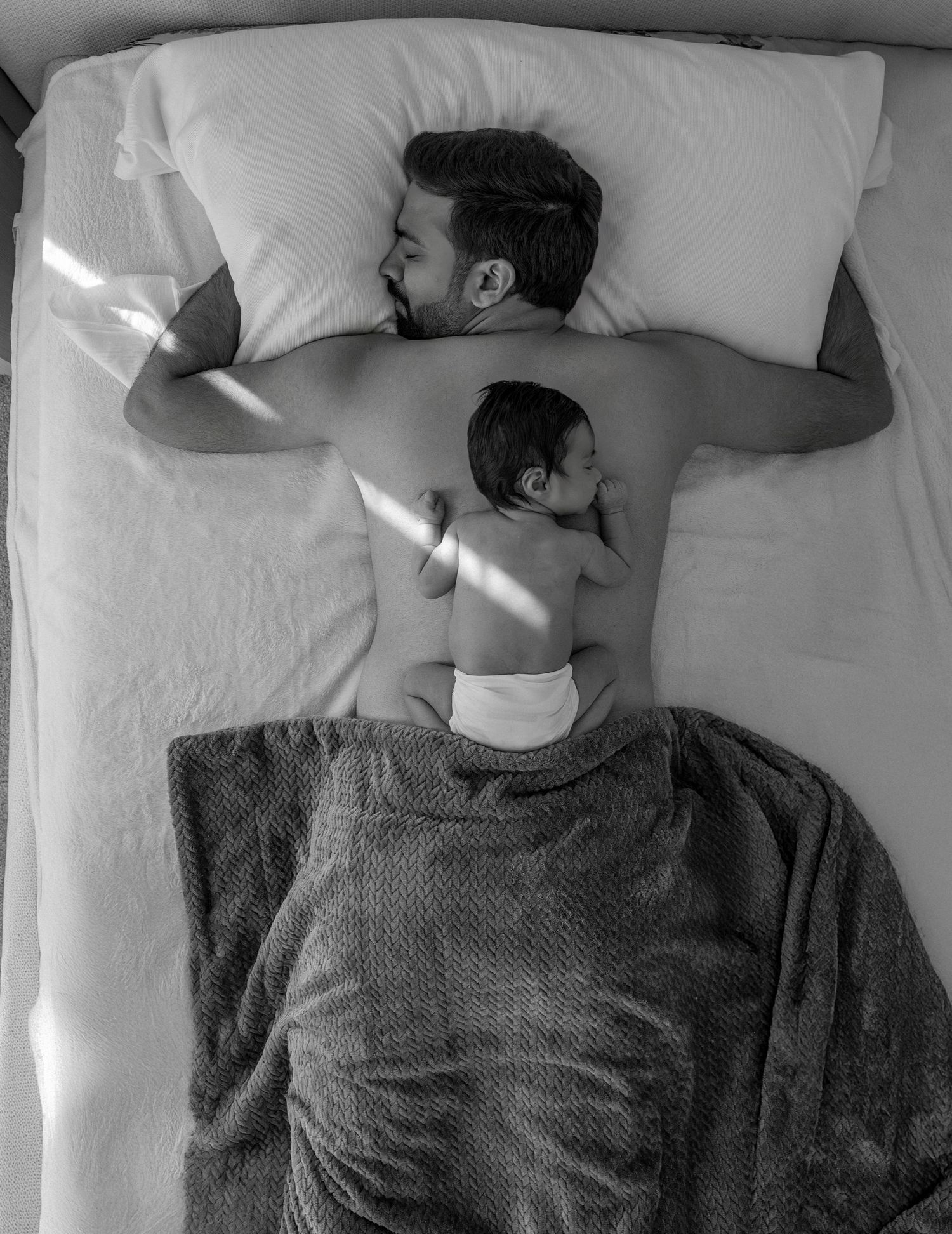 A series of black and white photos showing someone sleeping in different positions on white bedding.