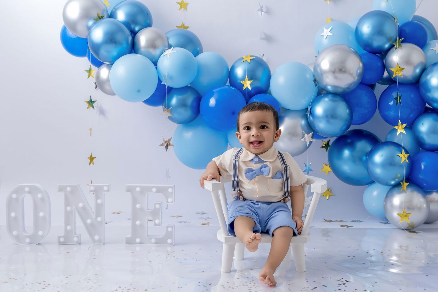 A festive blue and silver balloon arch with stars creates a magical first birthday photo backdrop setting.