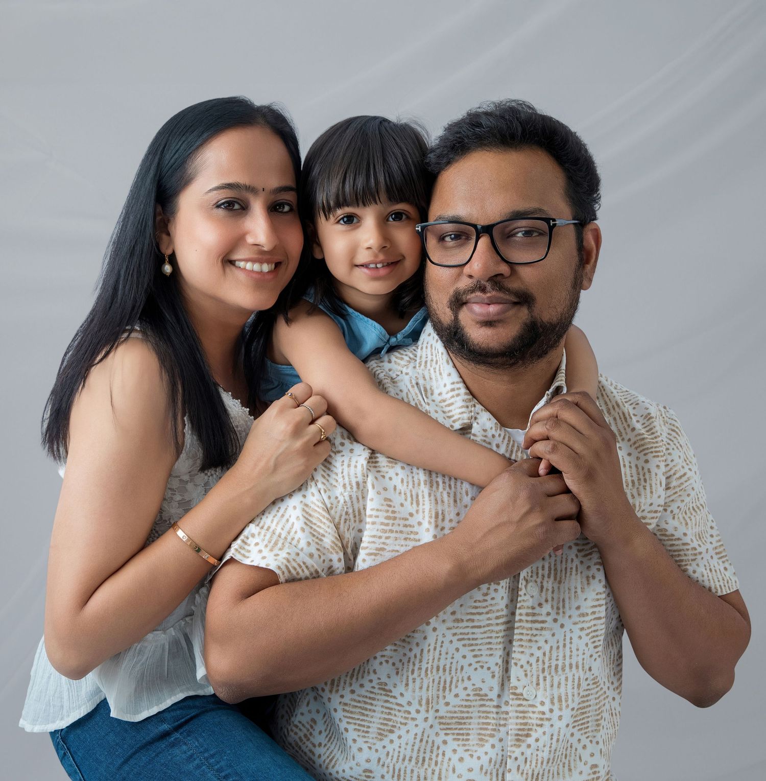 A family of three poses together in a series of candid black and white photos showing joyful expressions and hugs.