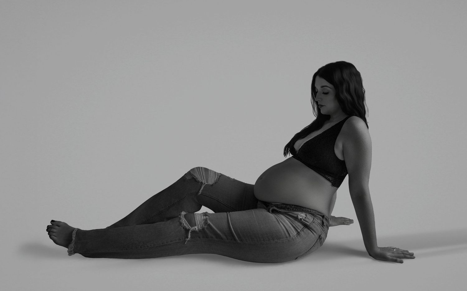 Black and white photo series showing a person in casual attire posing on the floor in various reclining positions.