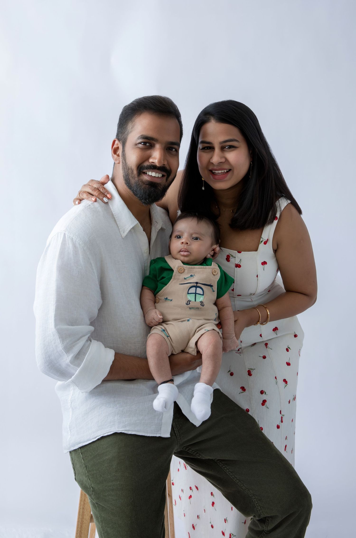 Family portrait in white and green outfits with baby in matching ensemble.