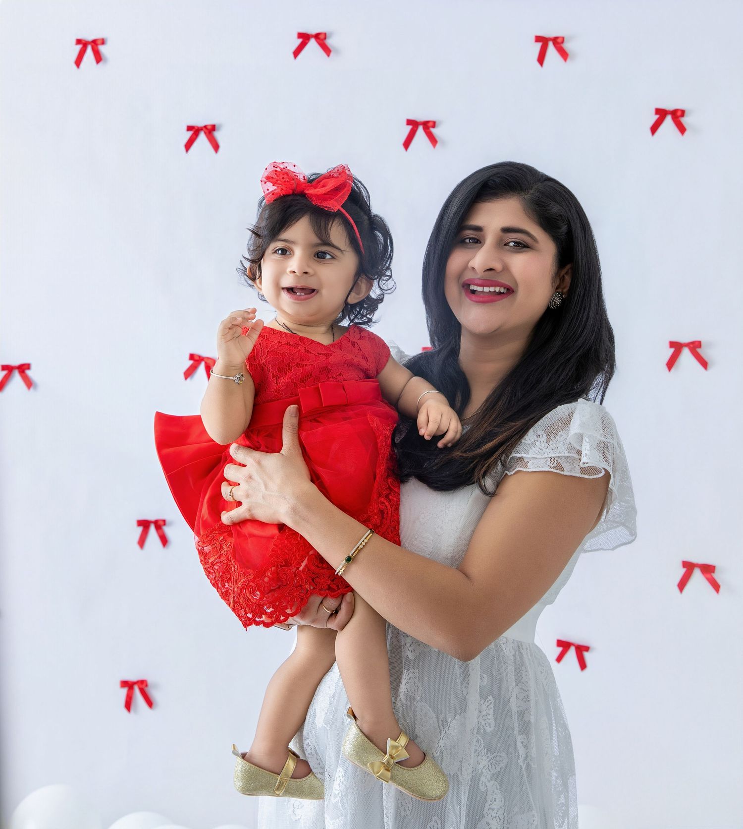 A joyful family portrait session with white balloons and red bow decorations in the background.