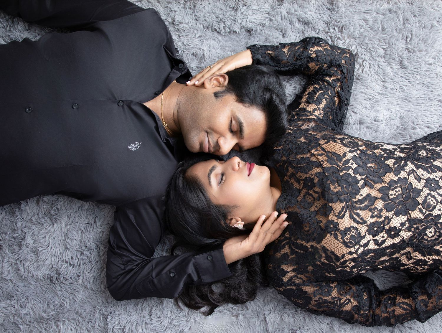 Elegant black lace dress portrait session against gray backdrop.