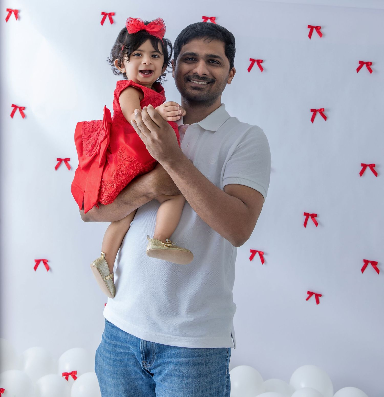 Candid family moments captured against a white background decorated with red bows.
