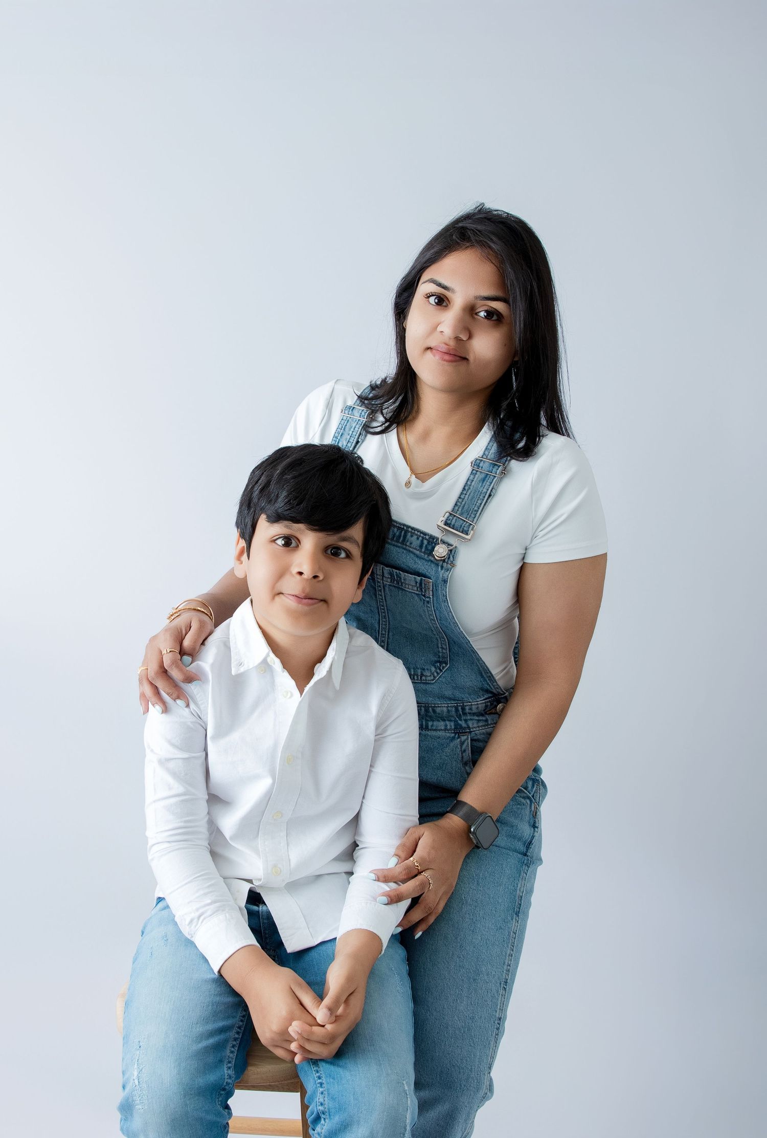 Intimate family portrait showing casual denim and white clothing in minimalist studio setting.