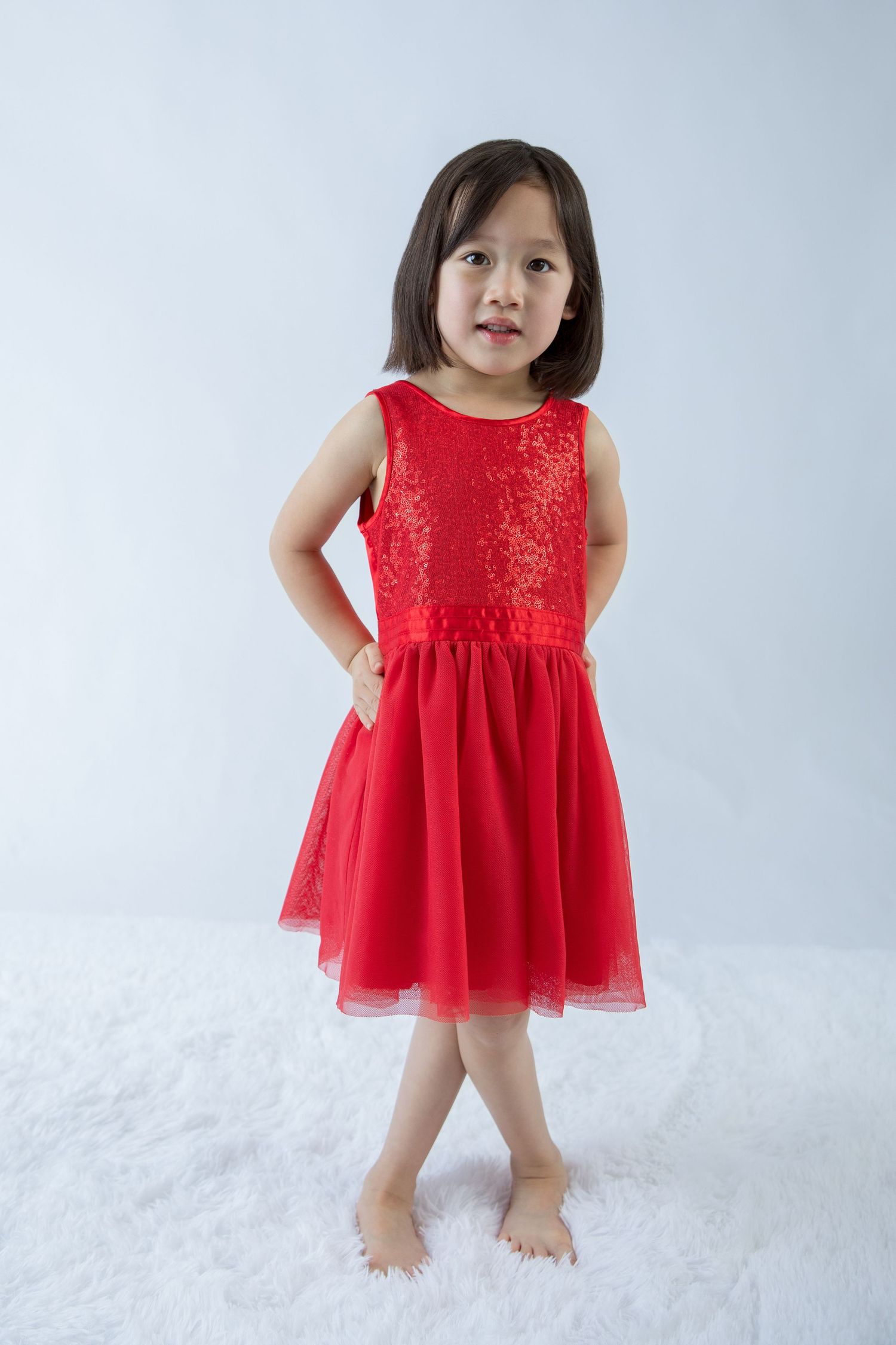 Red sparkly dress movement captured in studio photoshoot on light background.