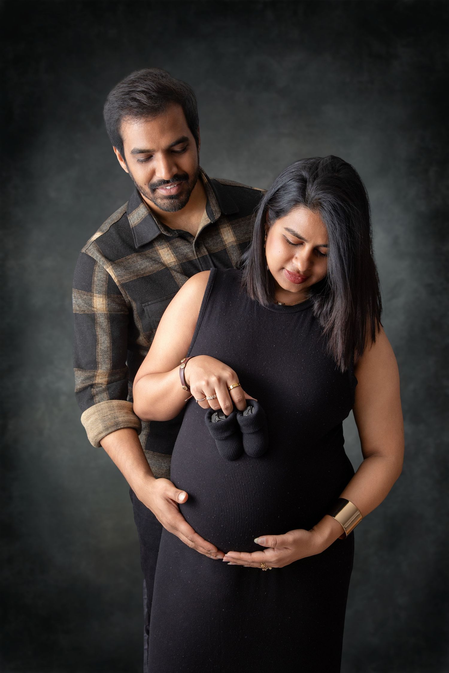 Tender maternity portraits against dark background showing intimate moments.