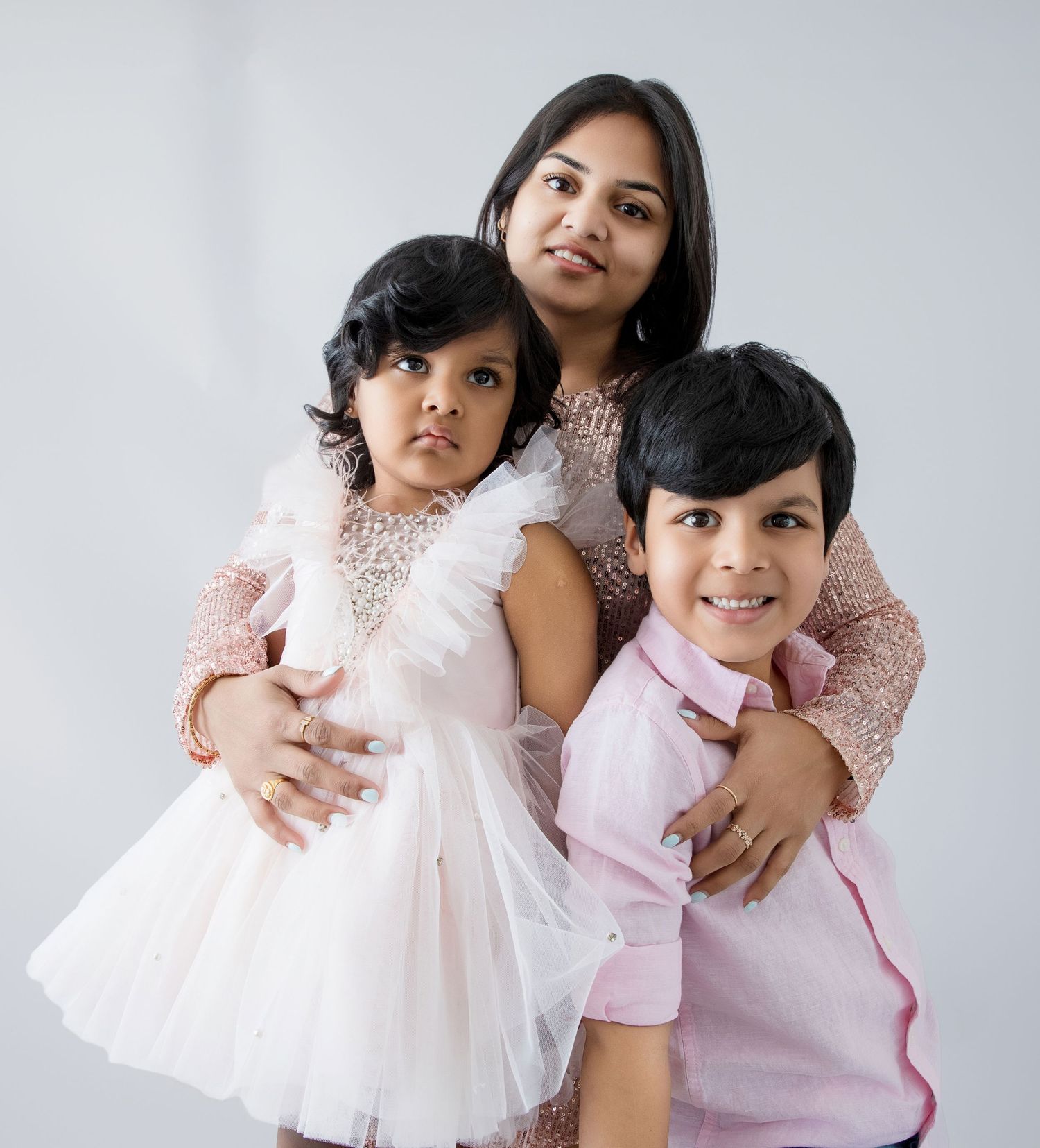 Sweet family portrait series with pink and white coordinated outfits against light background.