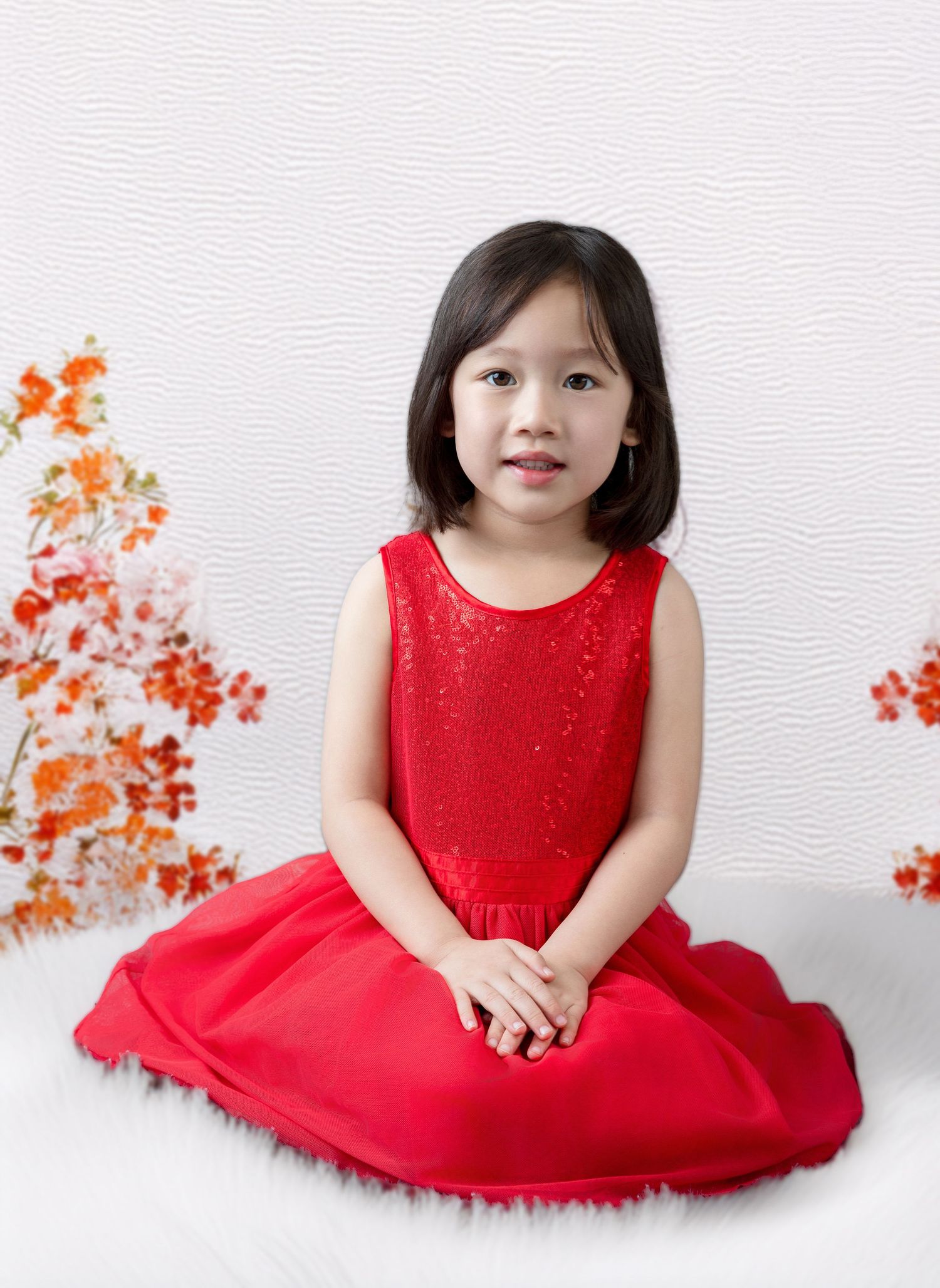 Beautiful red holiday dress photographed with orange floral accents in studio setting.