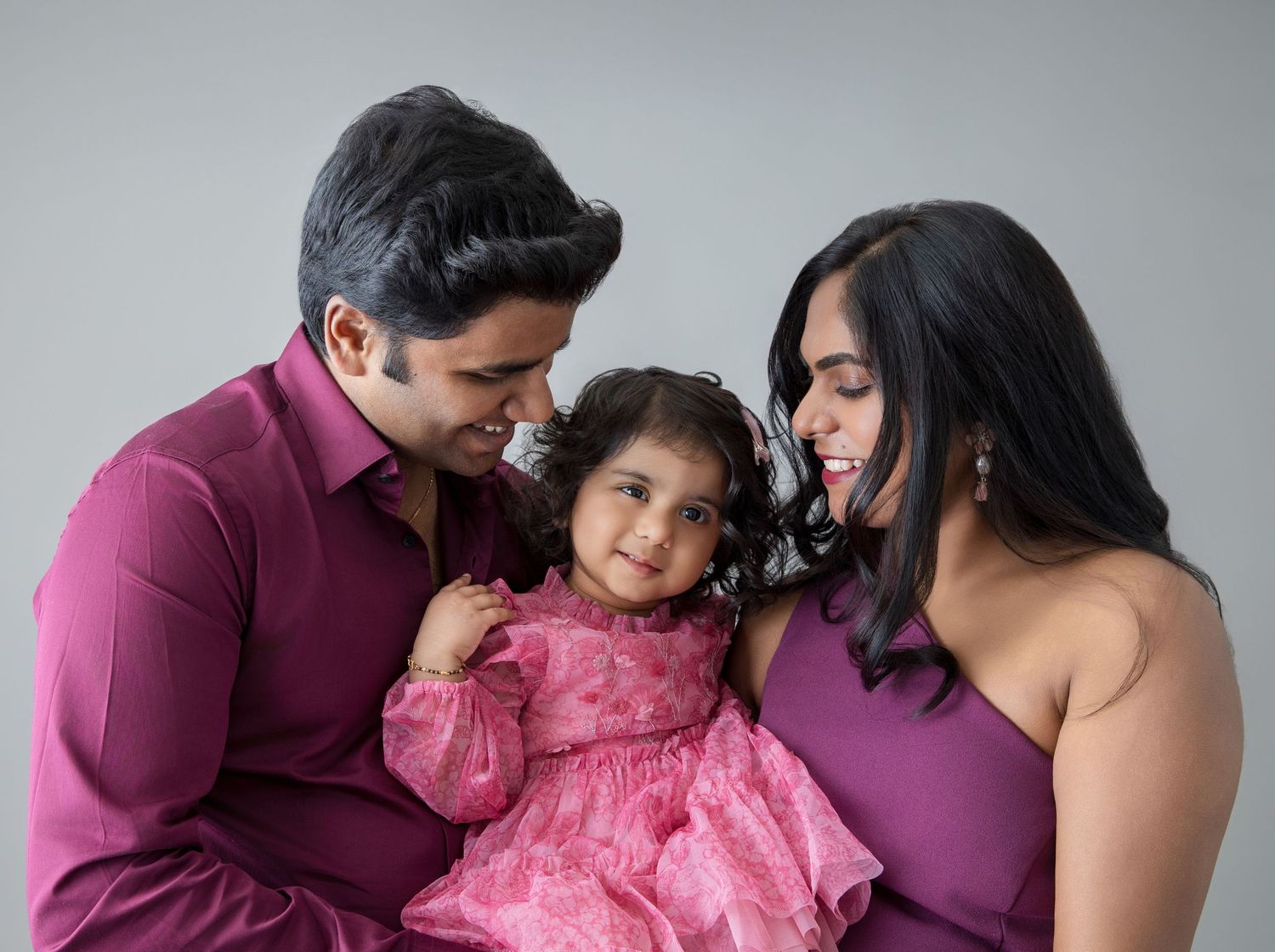 Family photo session featuring coordinated outfits and warm embraces in a professional studio setting.