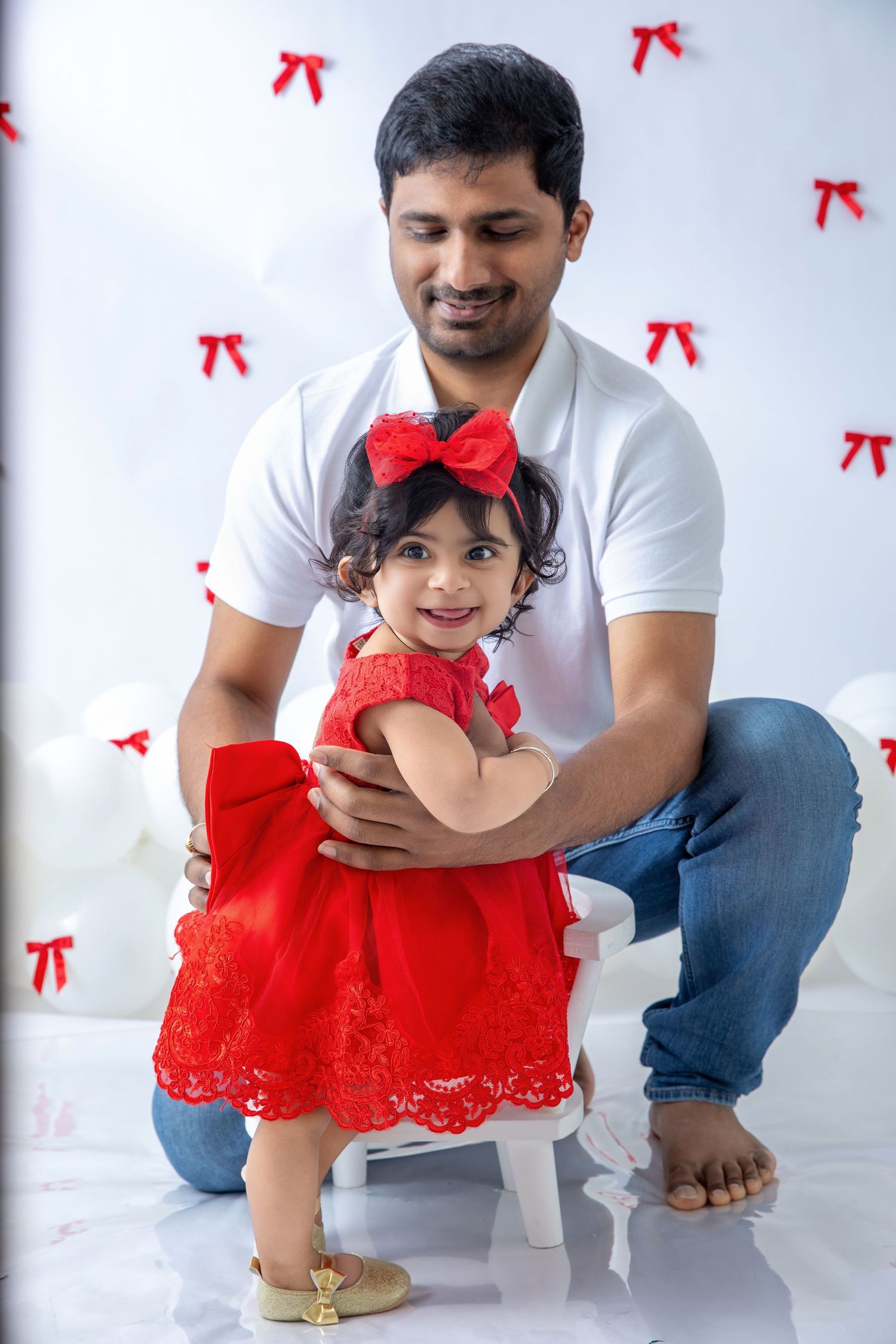 Parent and child sharing playful moment against white backdrop with red accents.