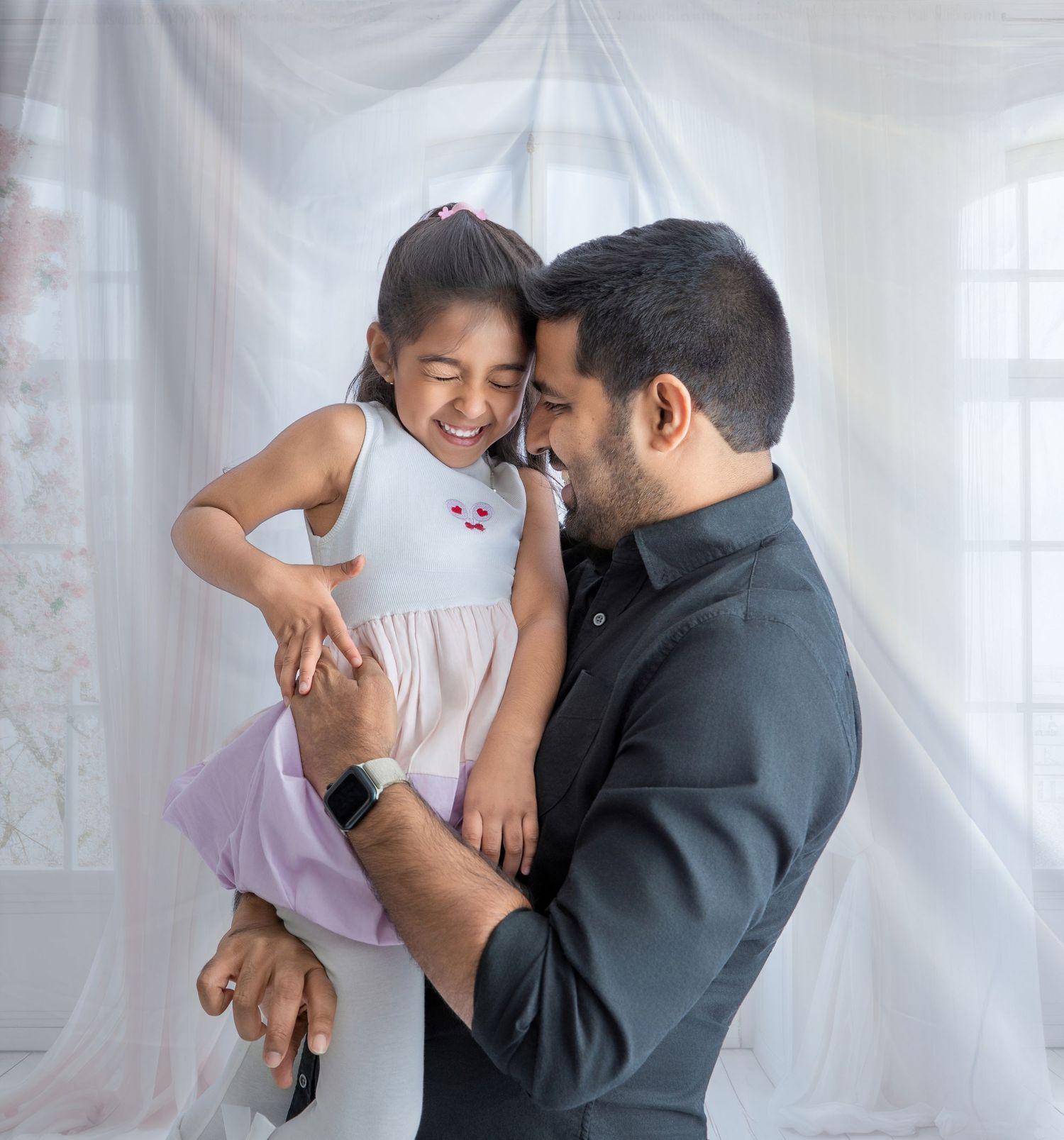 A parent and child share joyful moments together in a bright, white room.