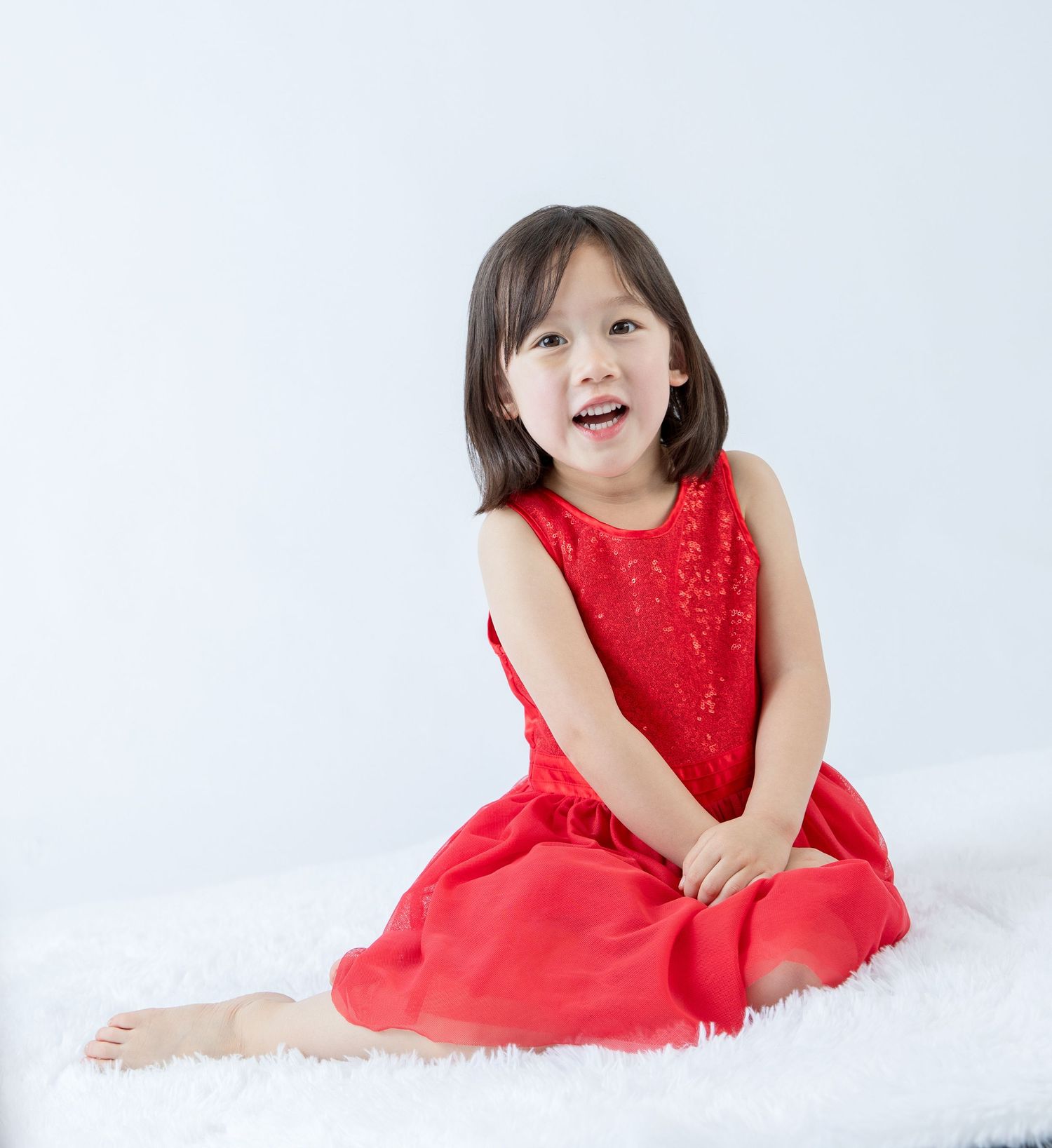 Joyful expressions captured during studio photoshoot in red party dress.