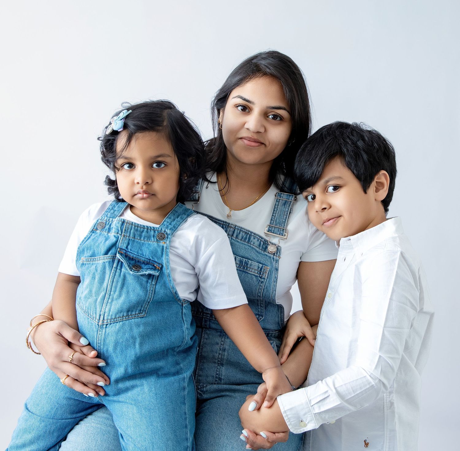 Casual family portrait featuring denim overalls and white shirts against a clean white background.