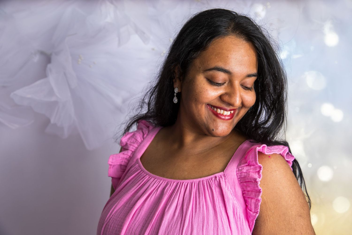 A soft pink ruffled summer dress photographed against a dreamy white textured background.