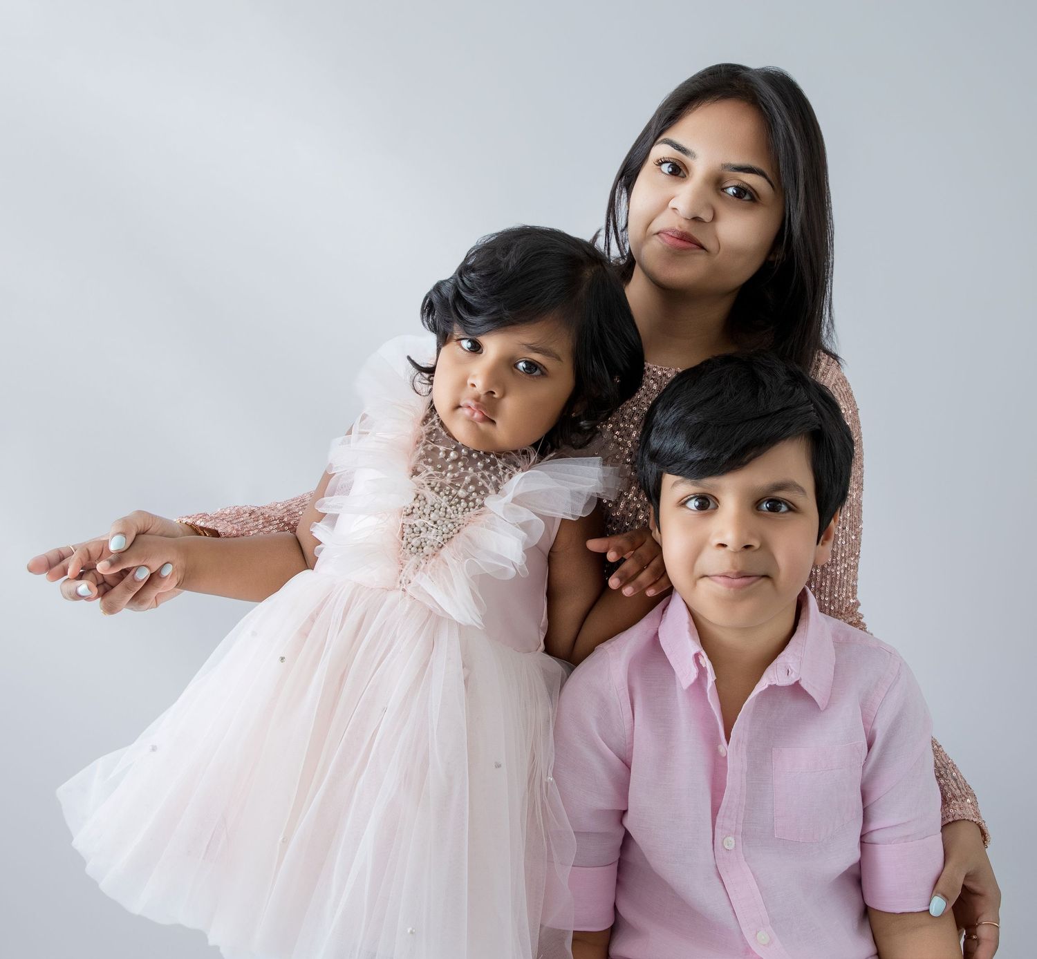Family photo series with coordinated pink and white outfits against minimalist backdrop.