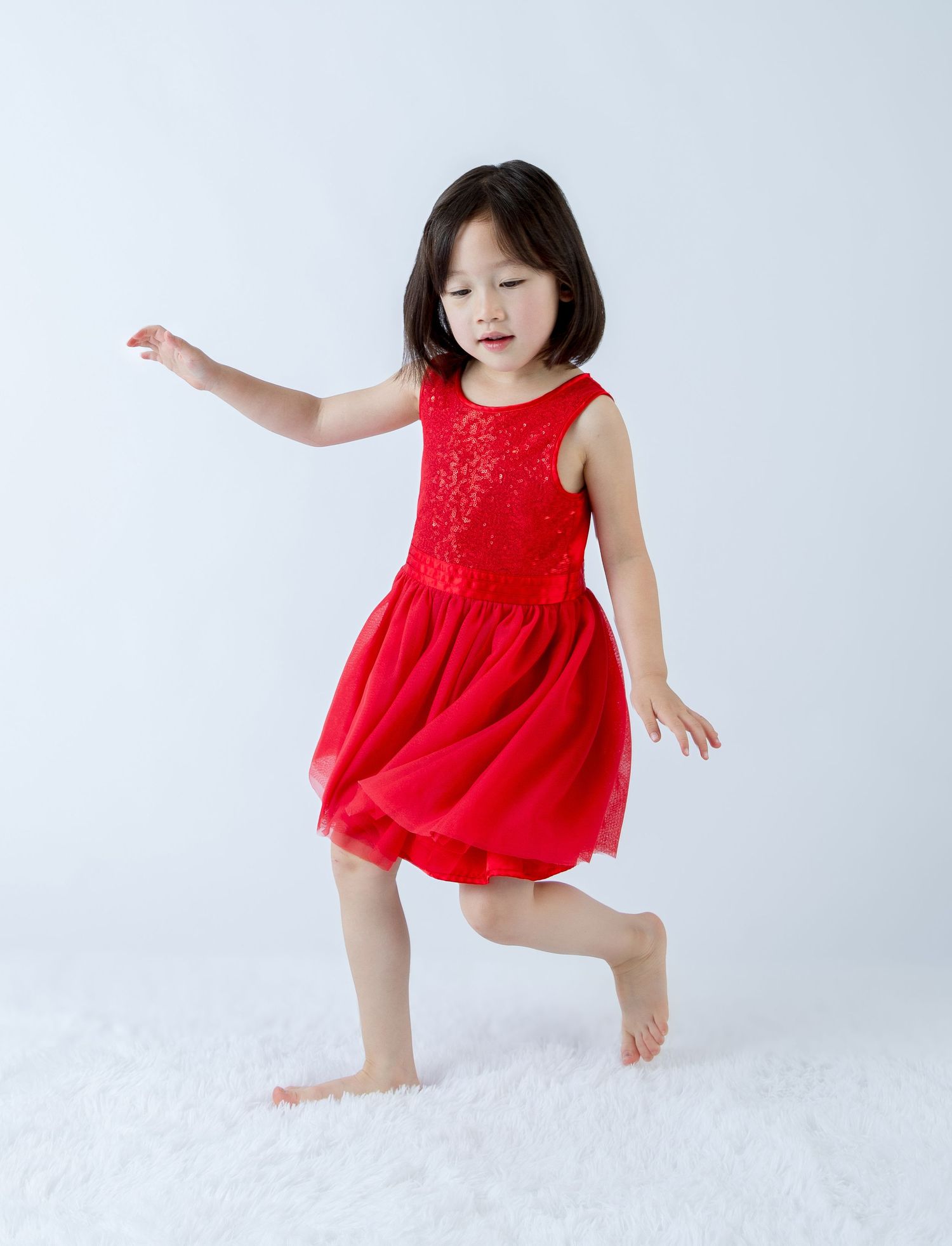 Dancing and jumping poses captured in bright red dress against white background.