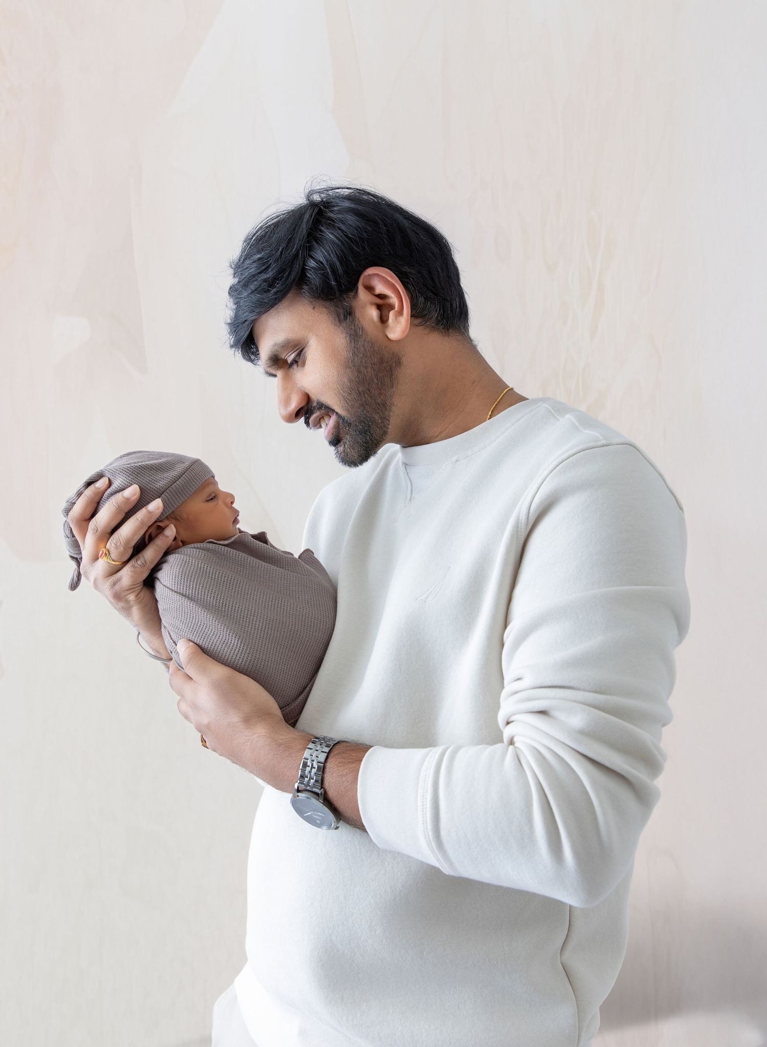 Person in white sweater expressing frustration and covering face with hands against light background.