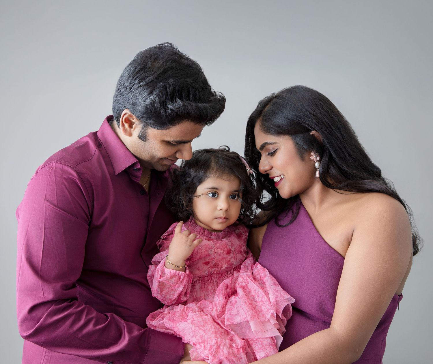 Professional studio photography session showing intimate family moments against grey backdrop.
