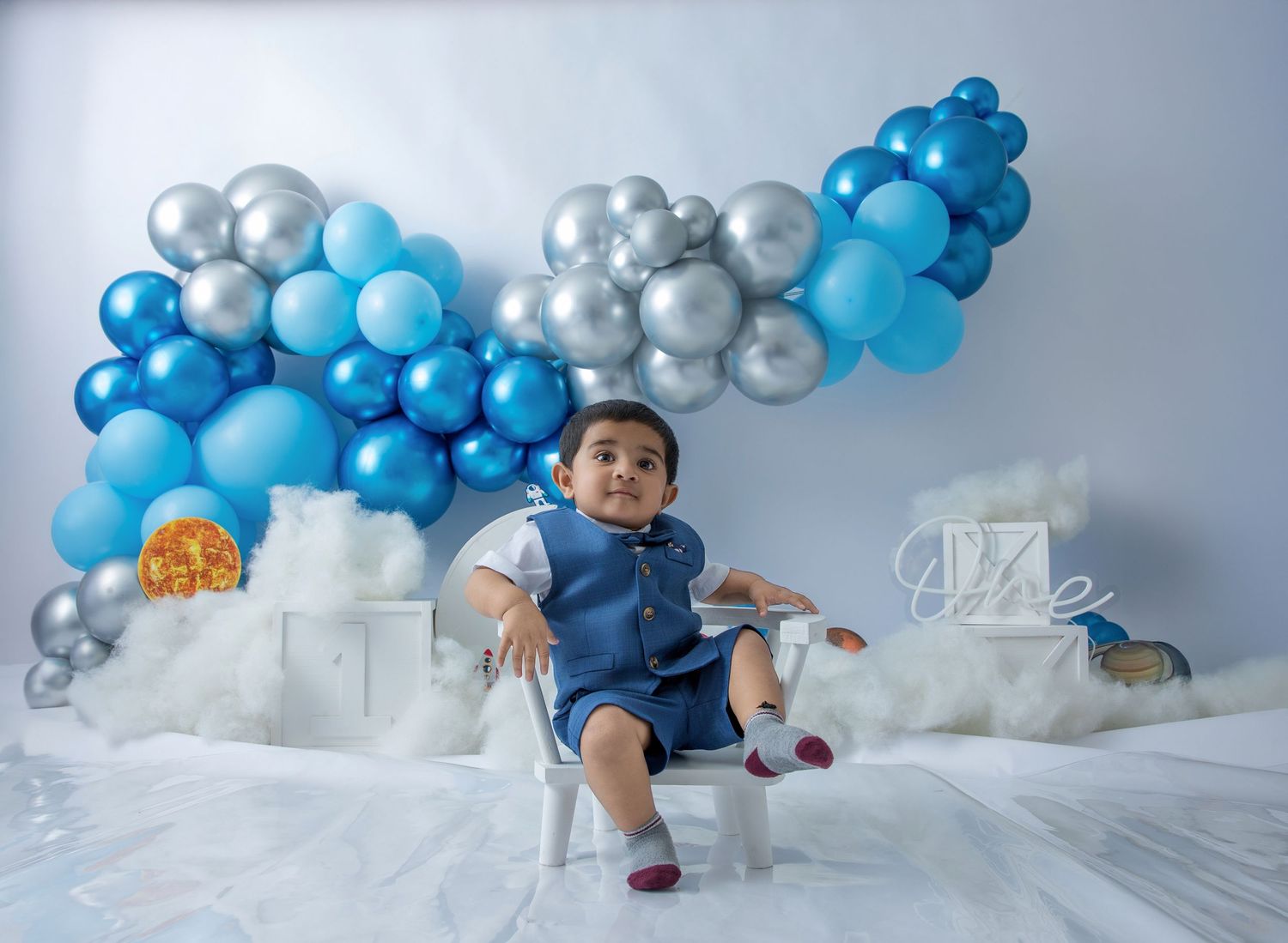 Series of photos showing cake smash progression with blue and silver balloon decorations in studio setting.