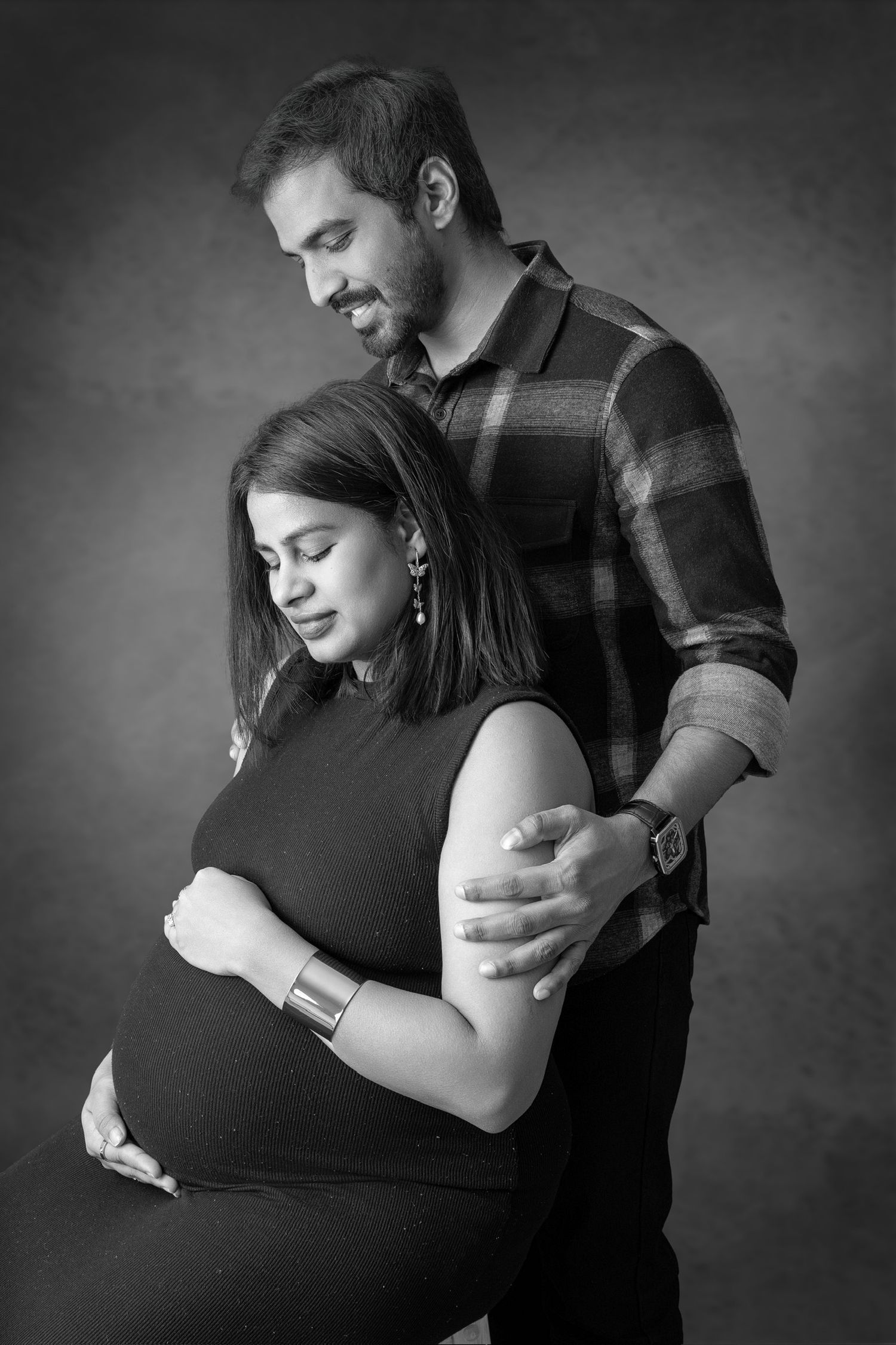 Black and white photos showing romantic couple embracing tenderly in emotional pregnancy photography session.