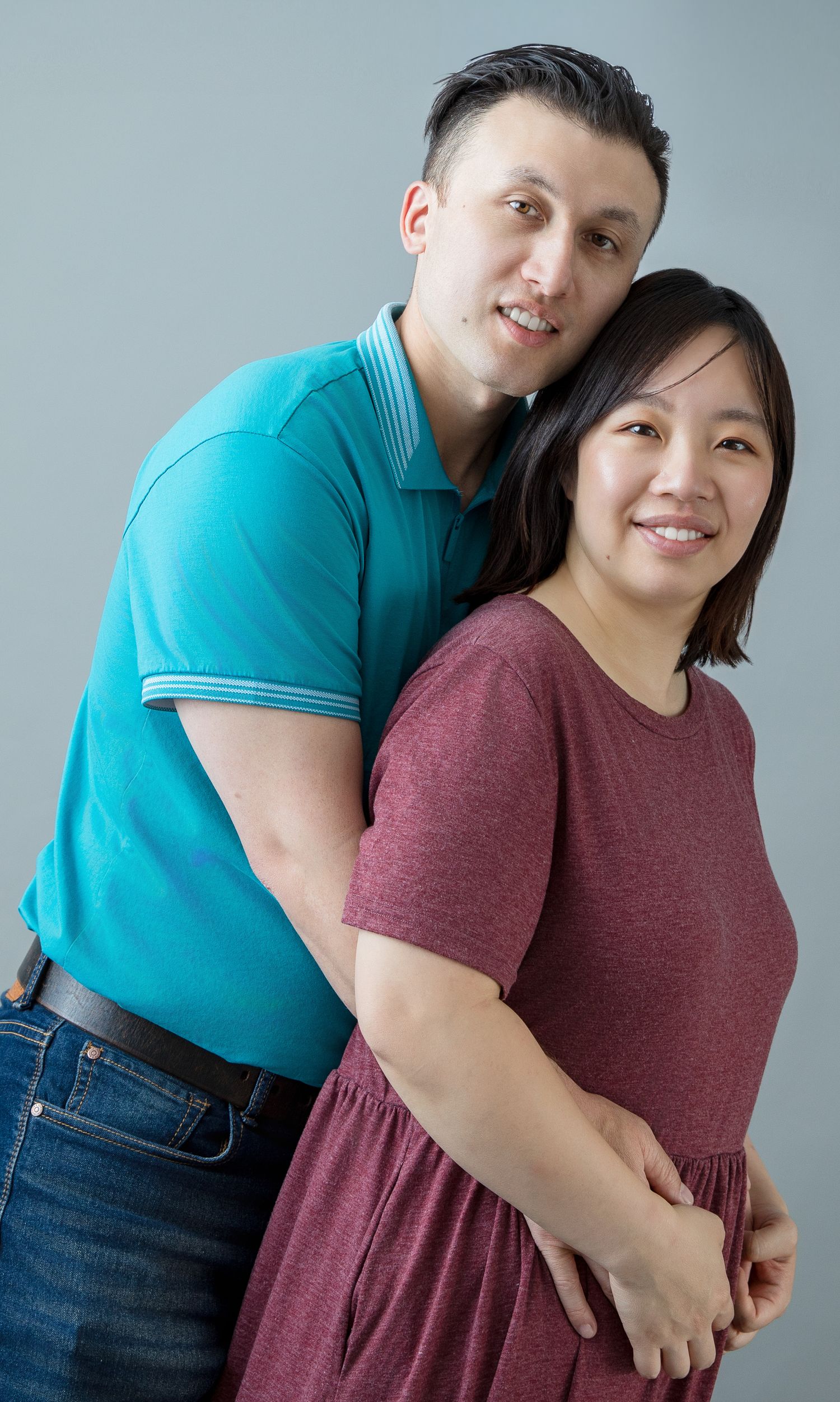 Intimate family portrait showing affection against studio backdrop.