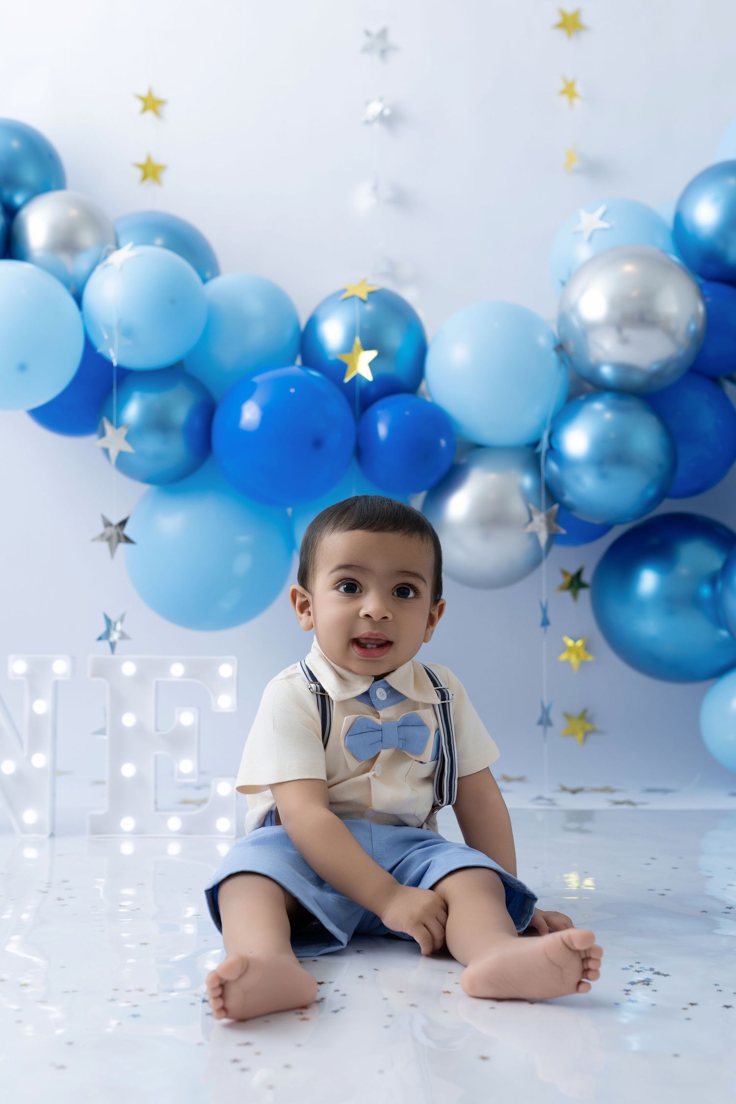 Festive party setup with blue and silver balloon arch and gold stars against white background.