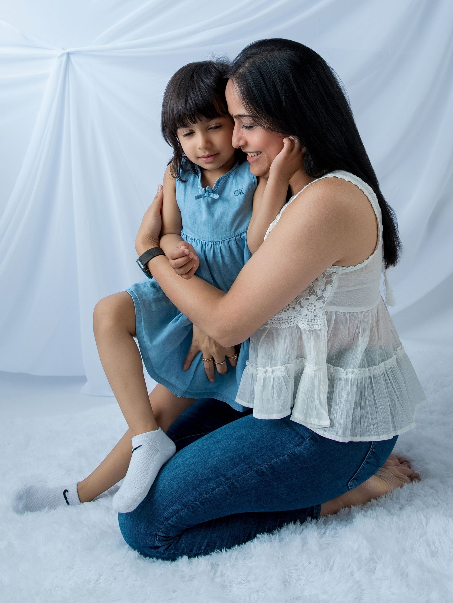 A tender family moment captured against a white backdrop showing affection and closeness.